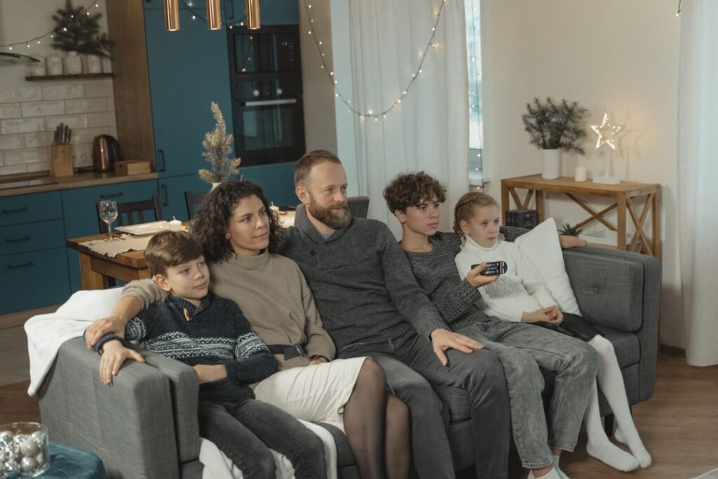 A family of five enjoying a warm evening on the couch at home.